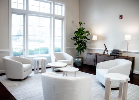 a living room with white chairs and tables and a large window at Broadlands Apartments in Ashburn, 20148